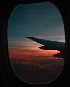 Airplane wing through airplane window at sunset